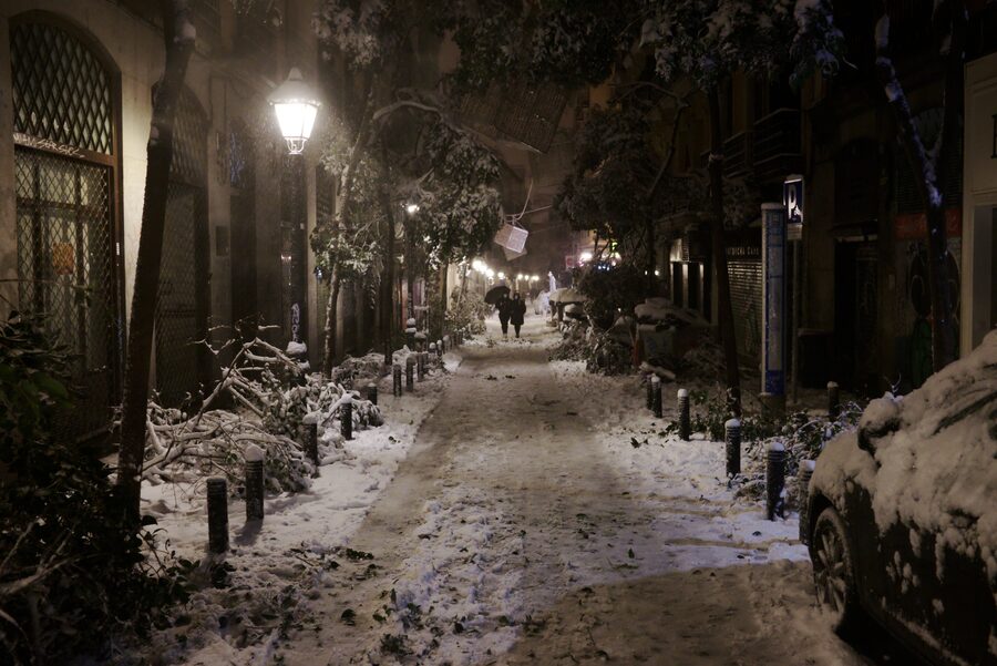 La calle del Pez de Madrid nevada y de noche, con ramas caídas y las farolas encendidas