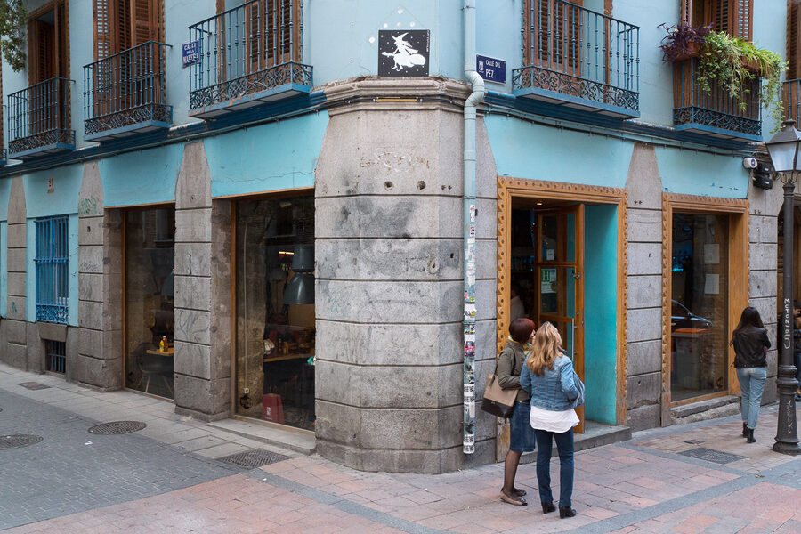Esquina de la calle del Pez con la calle de la Madera, con un local de fachada azul y la placa de la calle