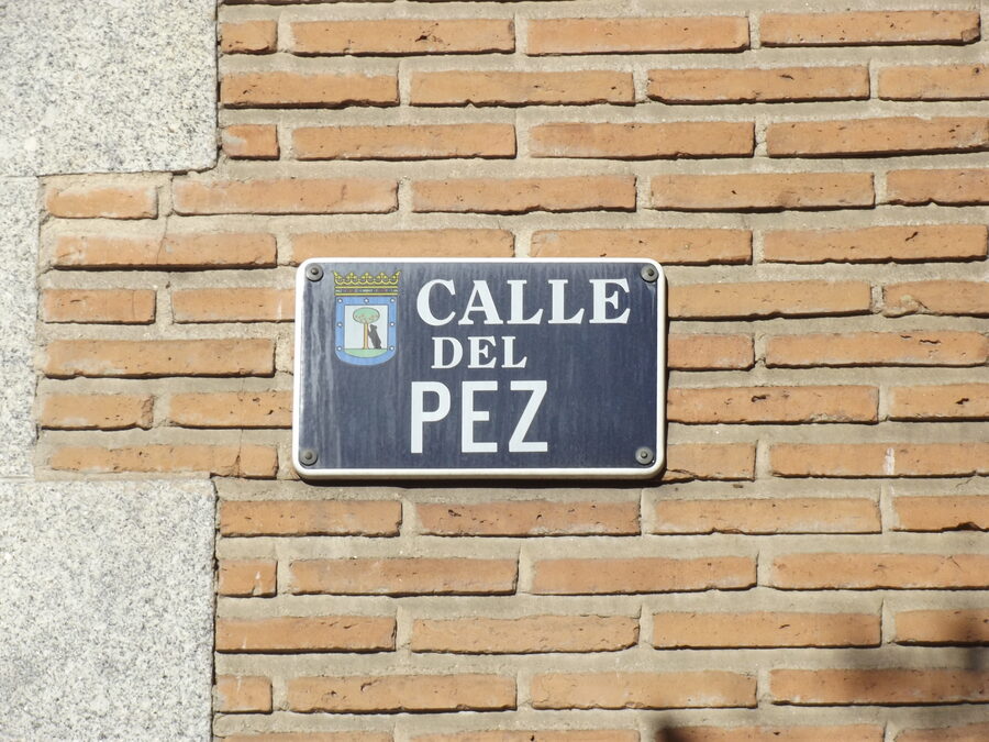 Placa de cerámica de la calle del Pez con el escudo de Madrid sobre una pared de ladrillo