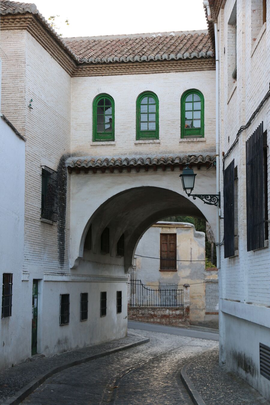 Calle estrecha del Albaicín de Granada con casas encaladas y arco de paso