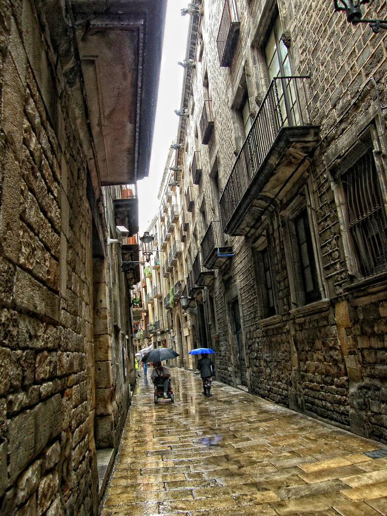 El carrer de Montcada de Barcelona, estrecho y empedrado, con las fachadas de piedra y el suelo mojado por la lluvia